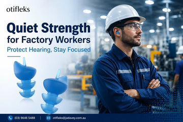Worker wearing noise-reducing earplugs in a busy factory environment